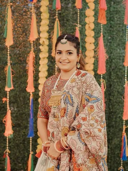 A textured ponytail for a bride at her pre-wedding event. The style is kept simple to complement her beautifully printed saree and the festive tassel backdrop.
