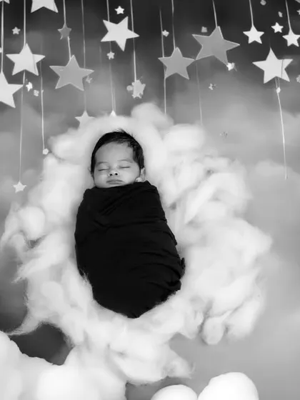 The same dreamy cloud theme in a classic black and white edit. This artistic choice creates a timeless and dramatic portrait of the sleeping newborn.