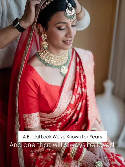 A bridal look we've known for years and one that will always be loved. This image captures the final touches, ensuring her red saree and soft glam makeup are perfect.