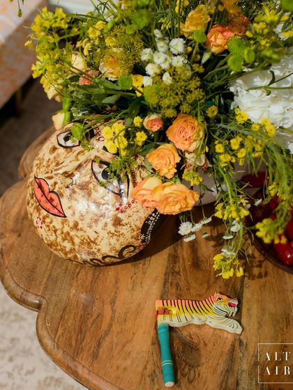 Details are everything. For the Haldi, I incorporated playful, handcrafted artifacts like this painted face vase and tiger clapper, adding a touch of whimsy and celebrating the work of local Indian artisans.