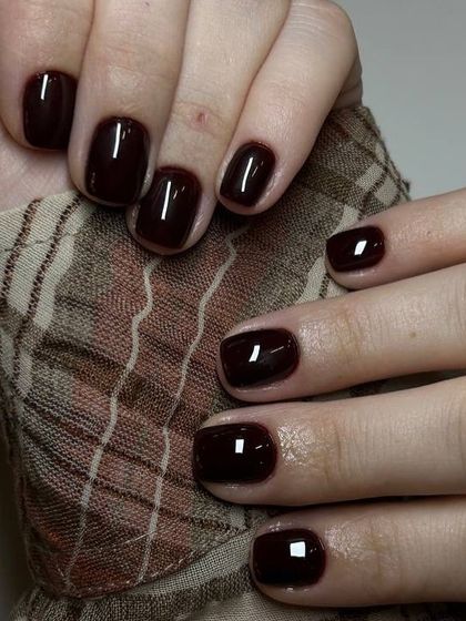 A classic dark burgundy manicure that complements the client's autumn-toned shirt perfectly. A great example of how nails can complete a look.