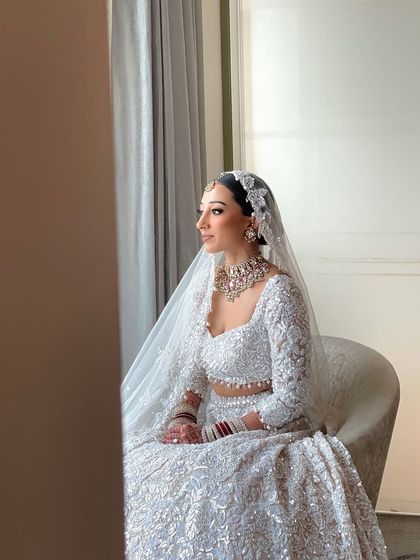 A beautiful, contemplative shot of the bride by the window. The low bun hairstyle gives an elegant and timeless feel, perfect for these classic bridal portraits.