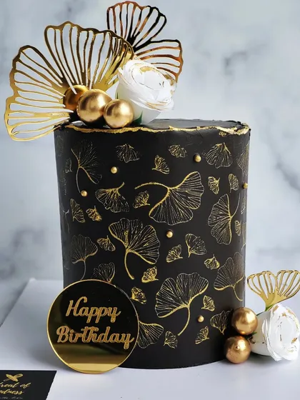 Black and gold is a timeless combination for a sophisticated celebration. This design features a delicate ginkgo leaf stencil in gold on a sharp, black buttercream cake, creating a look of pure, modern elegance.