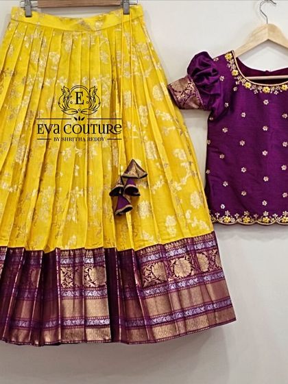 A deconstructed view of a yellow and purple Pattu Pavadai. The yellow brocade skirt is paired with a purple blouse with puff sleeves and butti work.