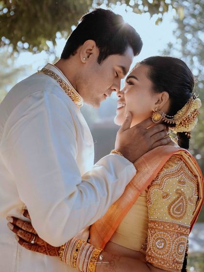 A tender moment between the couple, with the groom gently holding the bride's face. The soft backlighting adds a dreamy, romantic quality to the image.