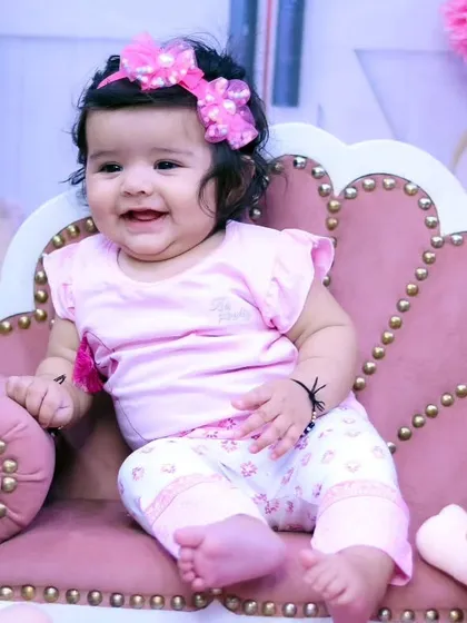 A happy baby girl in a casual pink outfit, enjoying her time in our studio.