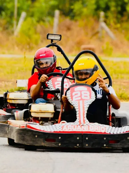 Two racers side-by-side, one flashing a peace sign. It's all about having a good time while pushing for the fastest lap.
