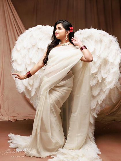 A stunning fusion of tradition and fantasy, with the mother-to-be wearing a beautiful white saree and majestic angel wings.