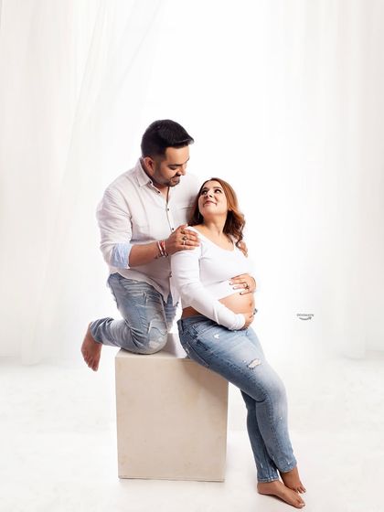 A tender moment in a casual, lifestyle-themed shoot. The couple, dressed in matching white shirts and jeans, share a loving look, creating a relaxed and authentic portrait.