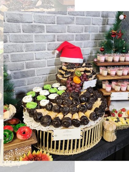 A festive Christmas dessert table featuring a chocolate cone tree, cupcakes, and dessert shots. A sweet and joyful centerpiece for any holiday party.