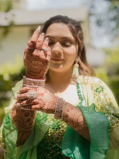 The intricate beauty of bridal mehndi. We focus on the details that tell your story, and the bride's henna-adorned hands are a canvas of tradition and anticipation. This close-up highlights the artistry and the quiet moments of the pre-wedding preparations.