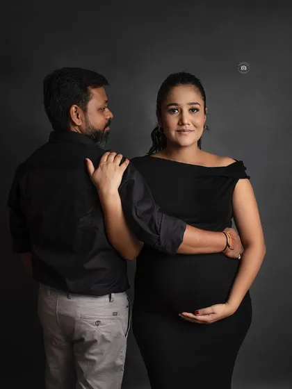 A classic and classy maternity portrait. The simple black outfits and dark grey backdrop create a sophisticated and timeless look.