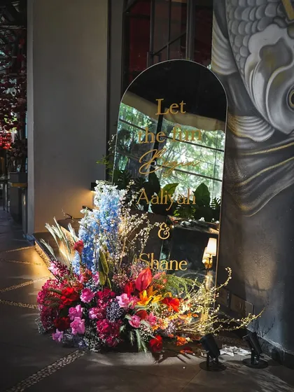 A mirrored welcome sign, framed with a riot of colorful flowers, greeted guests at this vibrant Mehndi party.