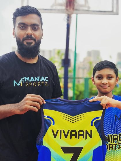 Coach welcomes Vivaan to the Maniac Basketball Academy, presenting him with his official team jersey.