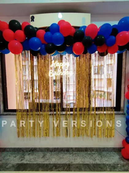 A simple yet effective Spiderman balloon decoration for a fan's birthday. The setup includes balloon pillars and a backdrop with gold fringe, perfect for a superhero celebration at home.