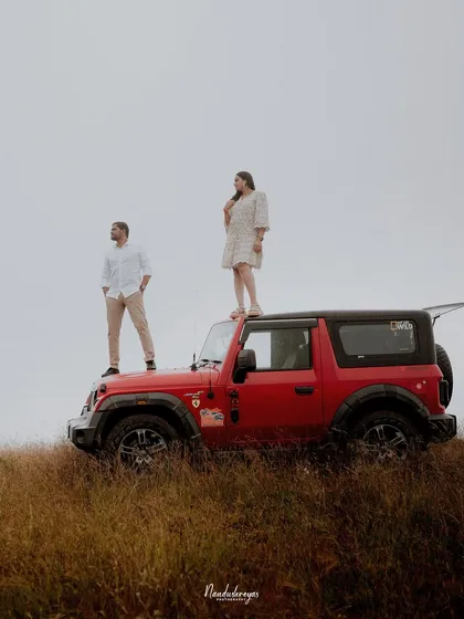 A powerful shot of a couple on their jeep against a stark, open landscape, showcasing a sense of freedom and shared adventure.