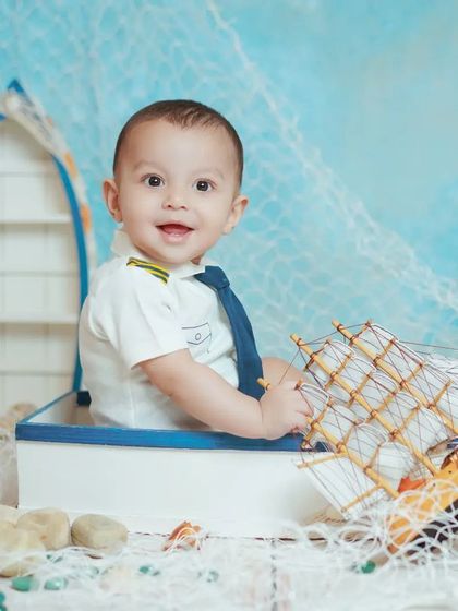 A happy little captain in his boat. The sailor theme is perfect for capturing your baby's adventurous spirit.