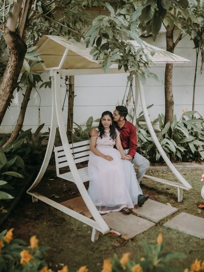 A romantic moment on a garden swing at a resort. The lush greenery and gentle kiss create a fairytale scene.