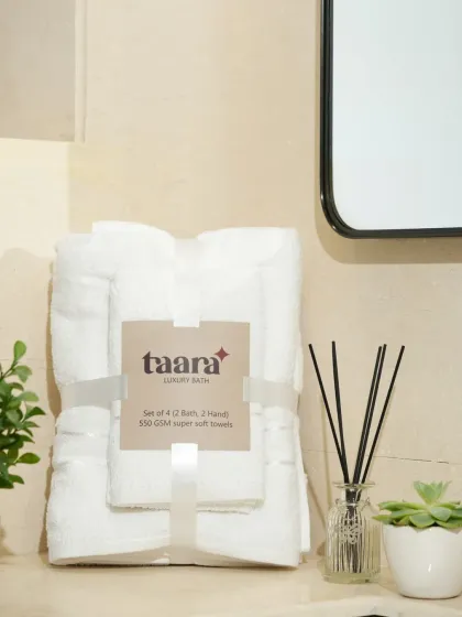 A vertically folded set of white towels next to a bathroom mirror. This shows an alternative way to display towels, giving a sense of a real home.