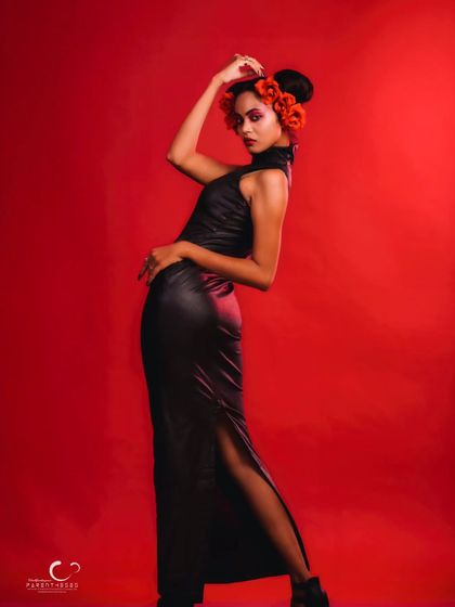 A powerful pose in a black leather dress, accented with red flowers. The red background creates a powerful, monochromatic color story.