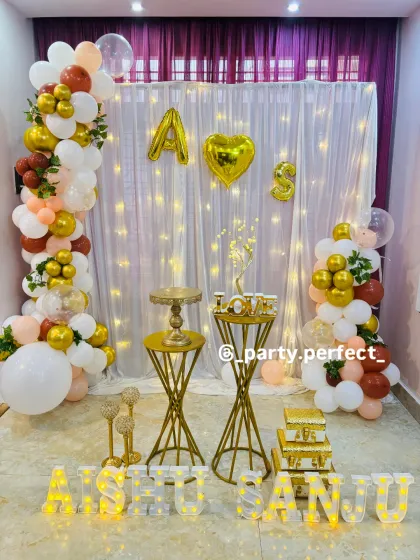 Personalization is key for making an event feel special. For this engagement party, I used foil balloons for the couple's initials and large marquee letters to spell out their names, 'AISHU SANJU', creating a custom backdrop against a curtain of warm fairy lights.