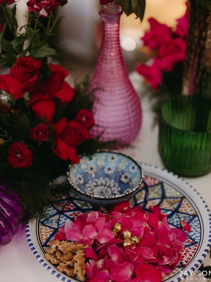 A close-up of the rich textures and colors at the Mehfil-e-Mehendi. Rose petals in a hand-painted bowl create a beautiful and traditional decor detail.