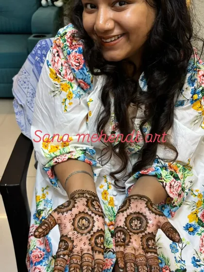 A happy client showing her beautiful lotus-themed mehendi. This design is perfect for festivals or parties.