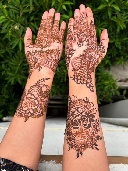 This design features a mix of bold floral work and delicate patterns, with a beautiful contrast between the filled and empty spaces. The outdoor lighting really makes the fresh henna pop.