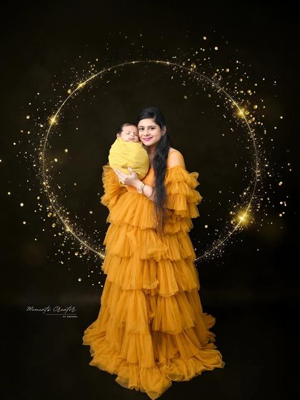 A magical mother and newborn portrait. She holds her baby, wrapped in a bright yellow swaddle, while standing in a sparkling circle of light, creating a truly enchanting image.