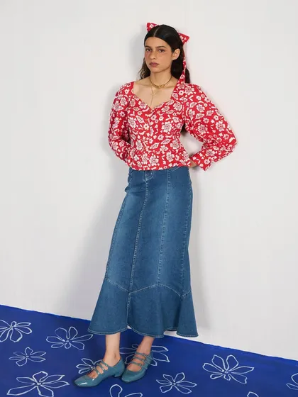 A full-length frontal view of the same look. The styling is youthful and fresh, combining classic denim with a feminine, printed blouse.