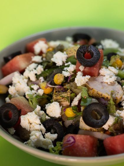 A close-up of the Watermelon Feta Chicken Salad, where you can see the chunks of fresh watermelon, crumbled feta cheese, grilled chicken, and black olives.