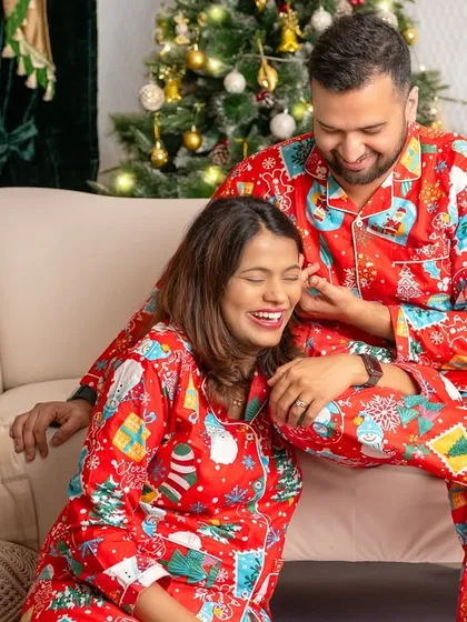 A candid shot of a couple sharing a laugh, dressed in festive pajamas, capturing the lighthearted joy of the holidays.