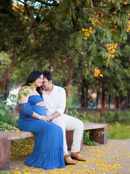 Sitting together on a park bench, surrounded by fallen yellow petals. This is a romantic and serene portrait of a couple enjoying a quiet moment together.