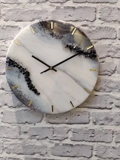 A full view of this 14 inch black, grey, and golden resin clock against a brick wall. The natural stone effect is perfect for modern interiors.