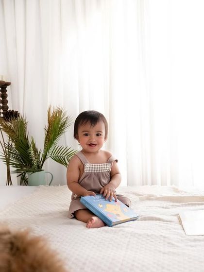 This adorable little bunny boy is sitting on a bed in a bright, light-filled room. This is a perfect example of a simple, lifestyle portrait that feels natural and unposed.