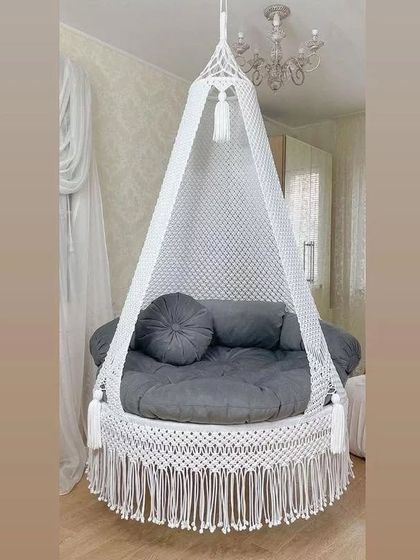 This all-white swing with a grey mattress and round cushion is a beautiful example of modern boho style. It looks elegant in any room.
