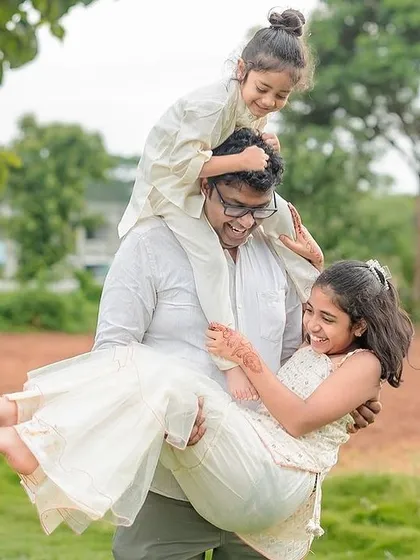 The pure fun of an outdoor family session. This playful shot of a parent lifting and carrying two laughing children perfectly captures the wild, happy chaos we love to photograph.