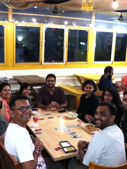 A large group gathers for a game night, sharing food and laughter. My cafe is designed to bring people together for fun and connection.