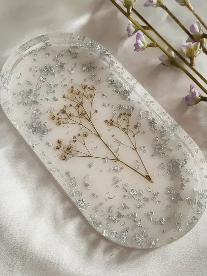 A clean shot of the oval trinket tray. The simple design with preserved baby's breath and silver flakes makes it a versatile piece that fits with any home decor style.