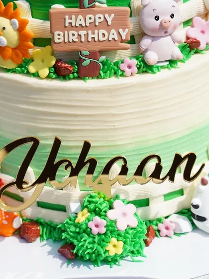 A close-up of the personalized "Yohaan" name topper and cute fondant animals on the farm-themed cake.