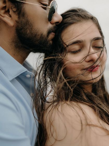 A gentle kiss on the forehead as the sea breeze blows through her hair. This close-up is all about capturing the tender and protective nature of their love.