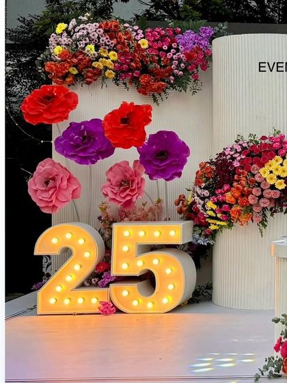 A detail shot of the light-up marquee number "25" nestled among colorful floral arrangements. This is a signature touch that highlights the milestone age in a beautiful and photogenic way.