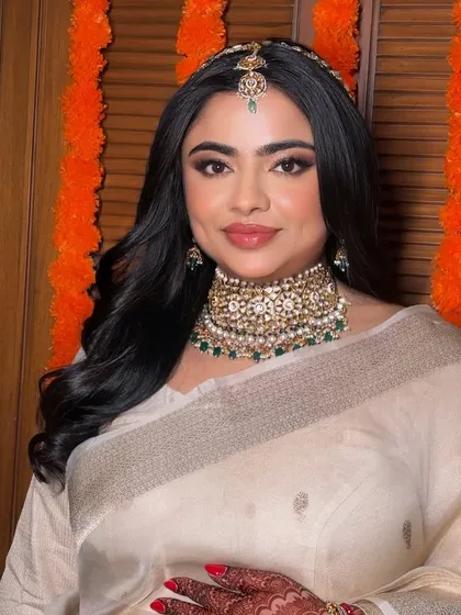 A beautiful bridal glow in an elegant ivory saree. The makeup is soft and defined, with a focus on the eyes and a traditional maang tikka.