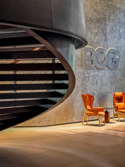 The lobby of the BCG Headquarters in Mumbai, featuring a dramatic spiral staircase that descends from a central cone. This space is organized around a circular, skylit courtyard, creating a powerful first impression that echoes Bombay's industrial heritage.