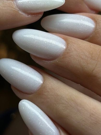 A shimmery, pearlescent white on long, almond-shaped nails. This elegant finish is perfect for brides or anyone wanting a touch of ethereal glamour.