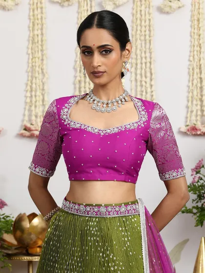 A close-up of the magenta blouse, featuring a unique neckline and intricate embroidery, paired with the olive green lehenga.