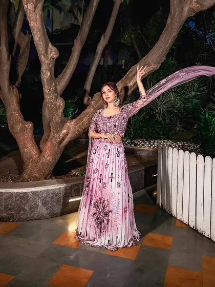 A playful and graceful pose. The flowing dupatta and the bride's happy expression capture the fun and excitement of a pre-wedding celebration.
