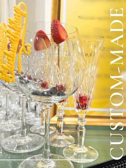 Custom-made celebrations are our specialty. This image shows our elegant crystal glassware prepared with fresh berries and personalized yellow stirrers, ready to be filled with a signature cocktail.