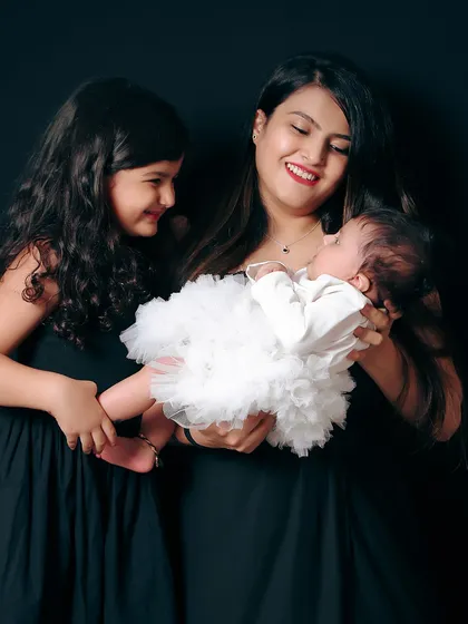 A tender moment between a mother, daughter, and the new baby. This image tells a story of growing love and the special bond between sisters.