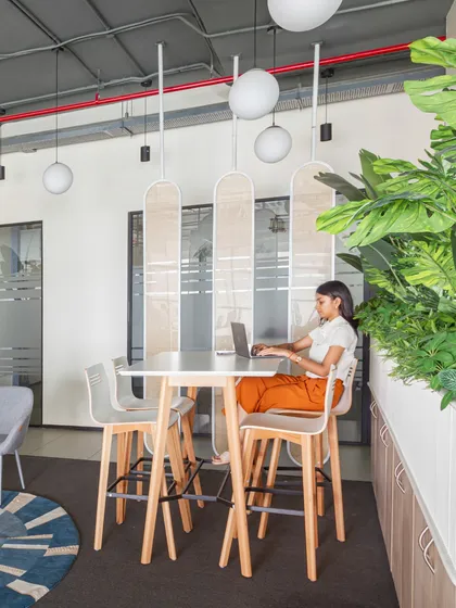 A high table within the breakout zone, perfect for collaborative work on a laptop or a quick coffee chat. The semi-private cane partitions provide a sense of enclosure without sacrificing light.
